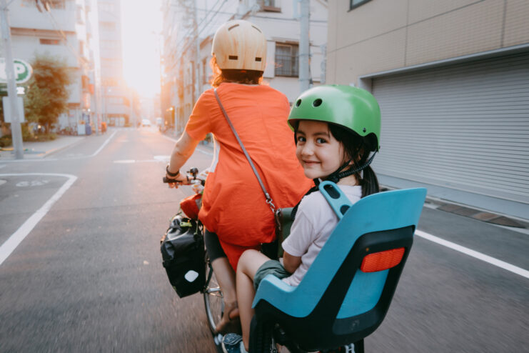 Mother cycling in Tokyo with her preschool child at sunset